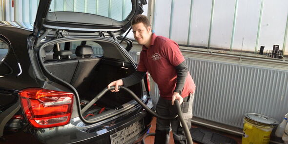 ein Schüler der KoBV saugt ein Autos mit einem Staubsauger aus