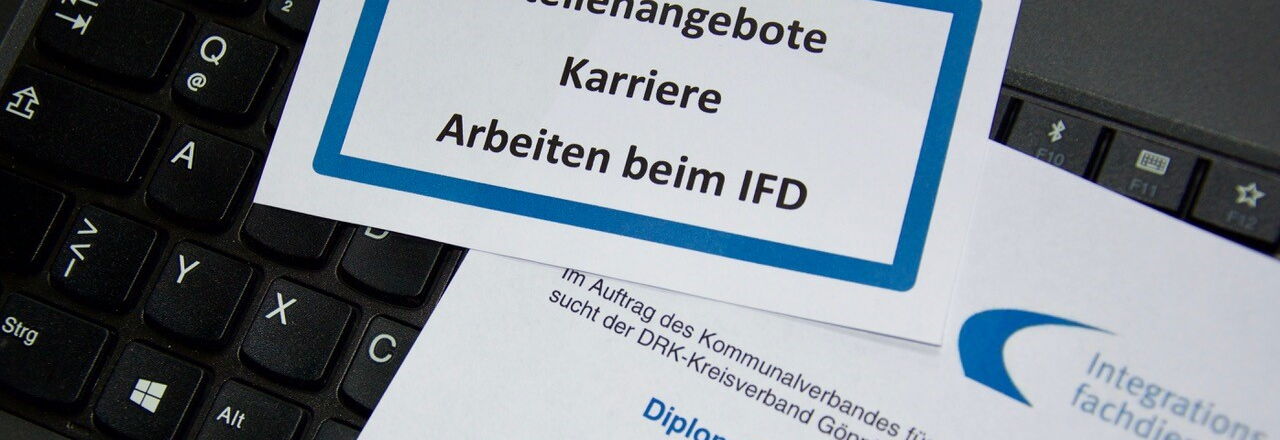 Muster eines Stellenangebotes liegt auf einer Computertastatur als Beispiel einer Bewerbung